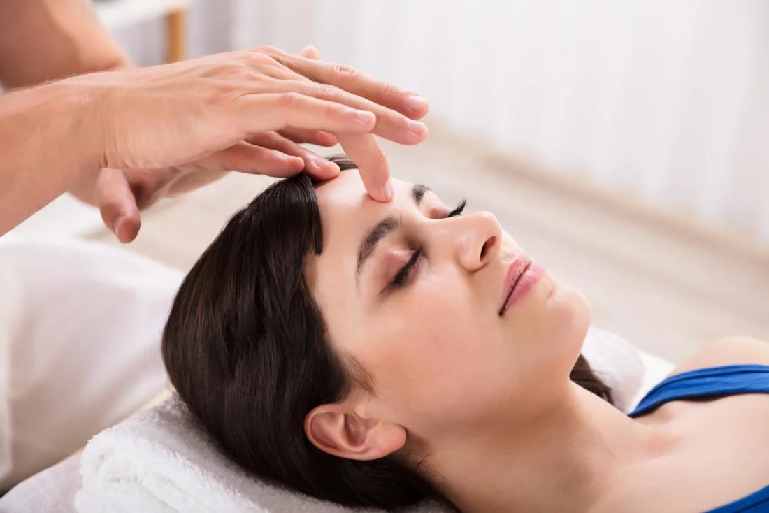 a woman receiving acupressure on the forehead for a headache